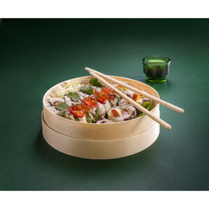 Drevené boxy na varenie Shushis 1 | Furodet Emballages Sushi podávané v okrúhlom drevenom paráku s paličkami položenými navrchu, na zelenom pozadí.