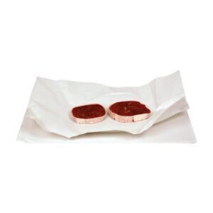 Two raw beef steaks resting on white parchment paper.